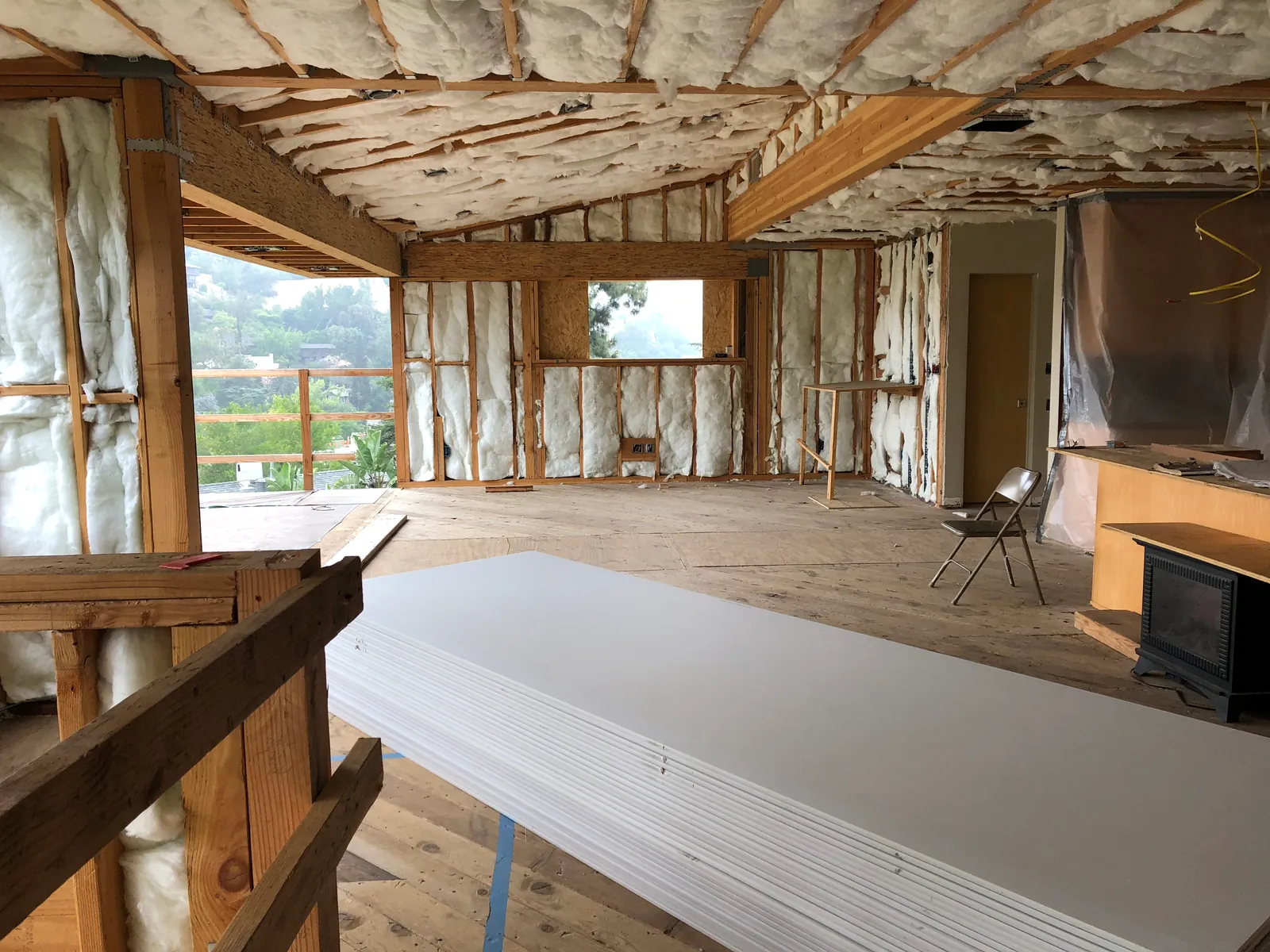 Sheets of gypsum board stacked in a framed hillside interior.