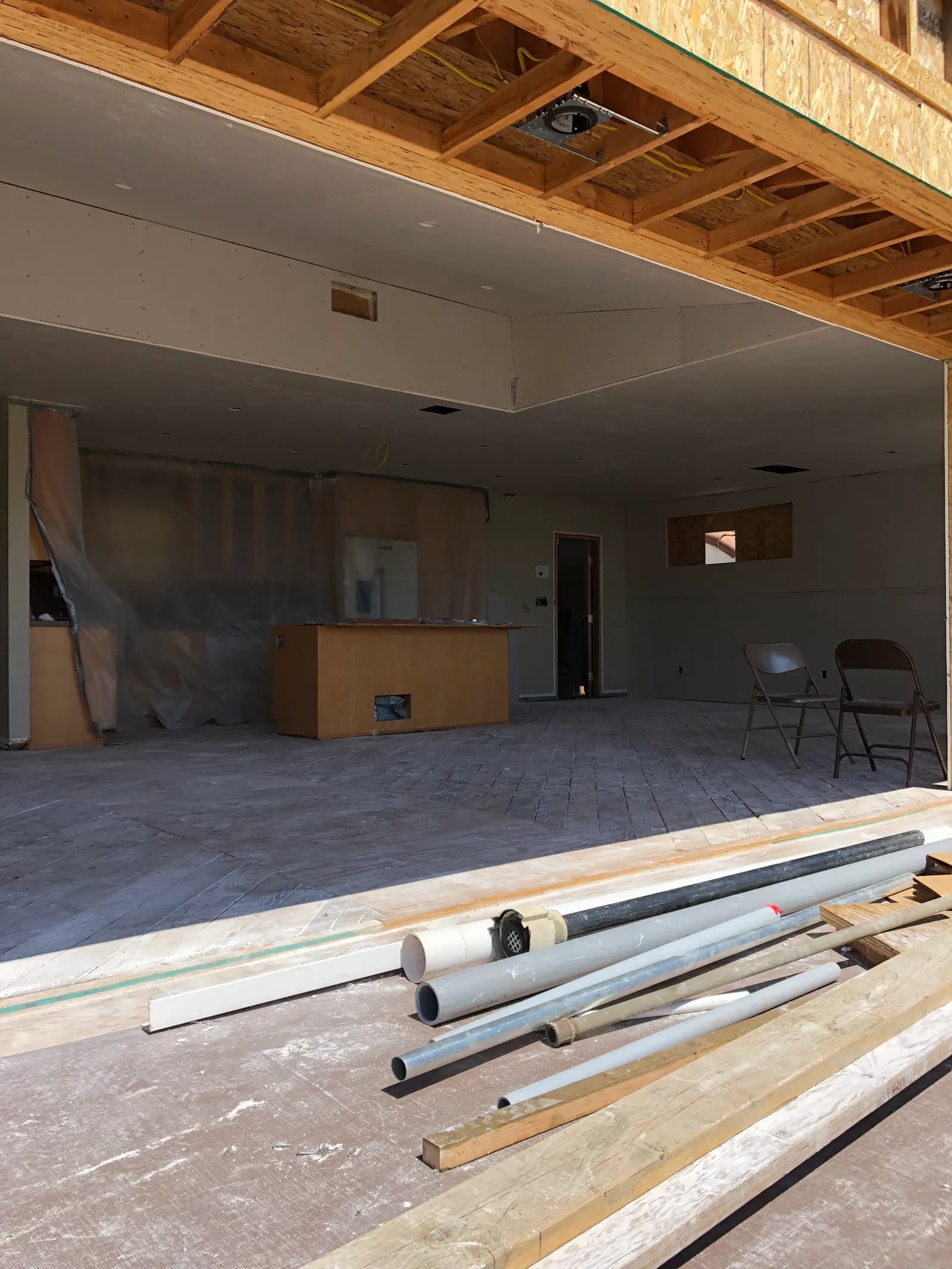 A hillside room with the ceiling boarded and floor protection down.